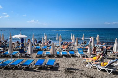 Costa Adeje 'de güneş yatakları ve şemsiyeleri olan siyah volkanik plaj. 08.01.2020 Tenerife, Kanarya Adaları