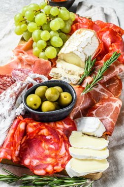 Üzümlü soğuk et, prosciutto, jambon, kurutulmuş et, sucuklu salam, fuet, camembert ve keçi peyniri. Gri arka plan. Üst görünüm