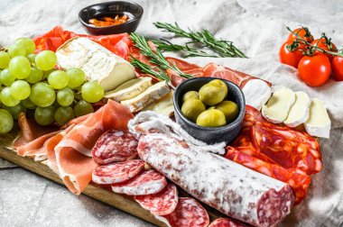 Üzümlü soğuk et, prosciutto, jambon, kurutulmuş et, sucuklu salam, fuet, camembert ve keçi peyniri. Gri arka plan. Üst görünüm