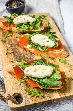 Keçi peyniri, roka ve armut reçeli baget ekmekli kanepeler. Gri arka plan. Üst görünüm