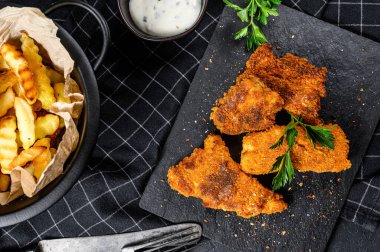 Balık ve patates kızartması, patates kızartması ve kızarmış balık filetosu. Siyah arka plan. Üst görünüm