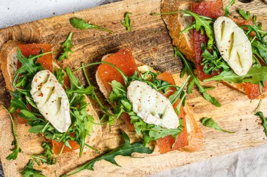 Keçi peyniri, roka ve armut reçeli baget ekmekli kanepeler. Gri arka plan. Üst görünüm