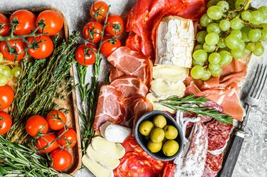 Üzümlü soğuk et, prosciutto, jambon, kurutulmuş et, sucuklu salam, fuet, camembert ve keçi peyniri. Gri arka plan. Üst görünüm