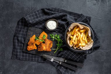 Balık ve patates kızartması, patates kızartması ve kızarmış balık filetosu. Siyah arka plan. Üst görünüm