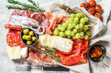 Üzümlü soğuk et, prosciutto, jambon, kurutulmuş et, sucuklu salam, fuet, camembert ve keçi peyniri. Gri arka plan. Üst görünüm