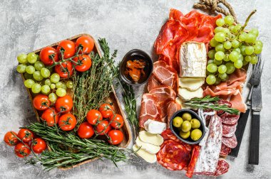 Üzümlü soğuk et, prosciutto, jambon, kurutulmuş et, sucuklu salam, fuet, camembert ve keçi peyniri. Gri arka plan. Üst görünüm