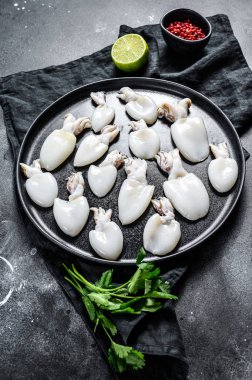 Biberiye ve maydanozlu taze mürekkep balığı. Siyah arka plan. Üst görünüm