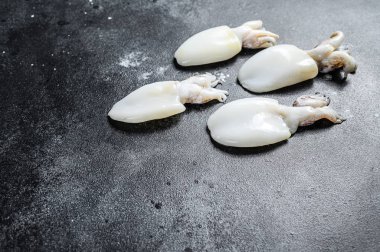 Masada çiğ küçük mürekkep balığı var. Siyah arka plan. Üst Manzara. Boşluğu kopyala