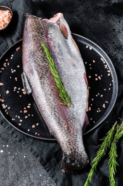 Kafasız, tuzsuz ve biberiyeli çiğ alabalık. Siyah arka plan. Üst görünüm
