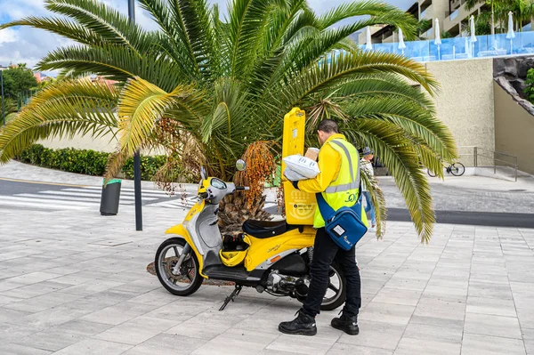 Sarı motosikletli bir postacı posta ve paket teslim eder. 08.01.2020 Tenerife, Kanarya Adaları