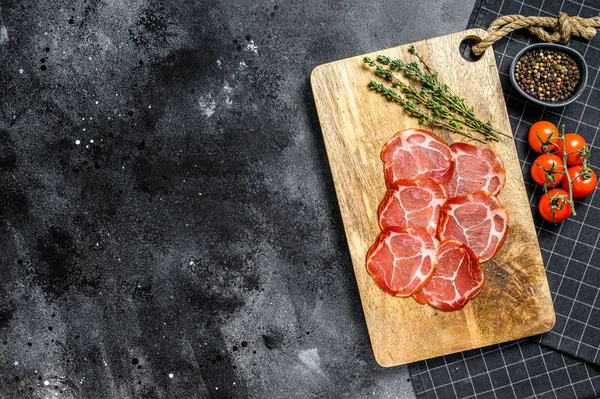 Raw smoked meat Jamon Lomo. Black background. Top view. Space for text — Stock Photo, Image