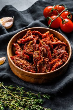 Sarımsaklı, baharatlı ve otlu kurutulmuş domates. Siyah, koyu arkaplan. Üst görünüm