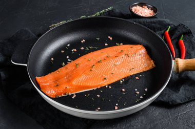 Tavada tuzlu ve biberli çiğ somon filetosu. Organik balık. Siyah arka plan. Üst görünüm