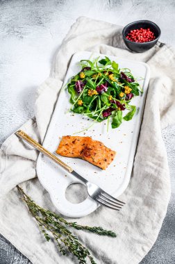 Arugula, marul ve kızılcıklı somon bifteği. Gri arka plan. Üst görünüm