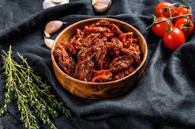 Sarımsaklı, baharatlı ve otlu kurutulmuş domates. Siyah, koyu arkaplan. Üst görünüm