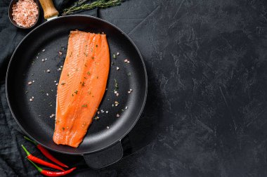 Tavada tuzlu ve biberli çiğ alabalık filetosu. Organik balık. Siyah arka plan. Üst Manzara. Boşluğu kopyala