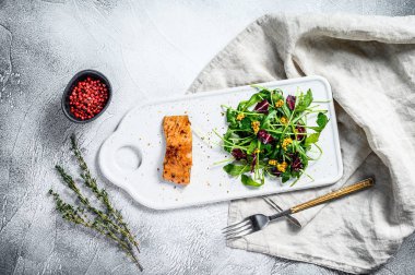 Arugula, marul ve kızılcıklı somon bifteği. Gri arka plan. Üst görünüm