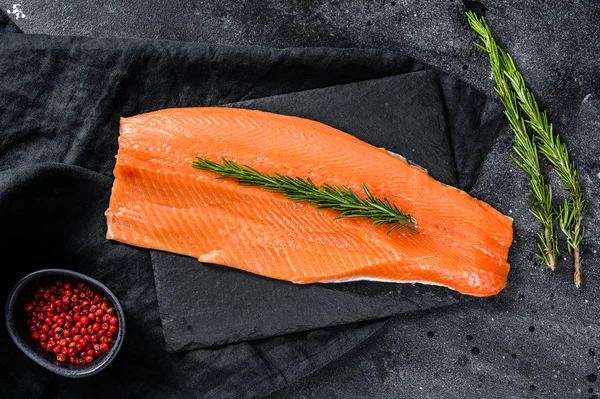 Rauwe zalmfilet met rozemarijn en roze peper. Biologische vis. Zwarte achtergrond. Bovenaanzicht — Stockfoto