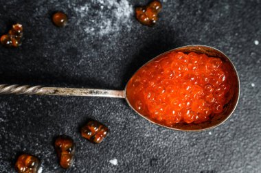 Lezzetli bir kaşıkta somon kırmızısı havyar. Siyah arka plan. Üst görünüm