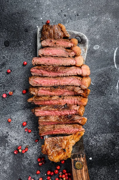 Gegrilde biefstuk op een hakmes. Het kookmedium. Zwarte achtergrond. Bovenaanzicht — Stockfoto