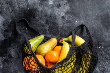 Meyvelerle dolu, çevre dostu, yeniden kullanılabilir bir torba. Eko dostu, plastiksiz. Siyah arka plan. Üst Manzara. Boşluğu kopyala