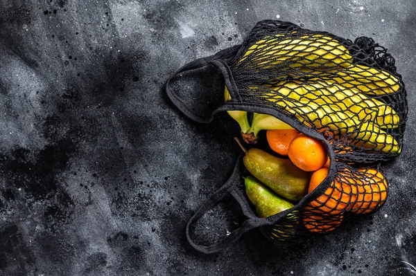 Bolsa de cordones reutilizable ecológica, llena de frutas. Ecológico, libre de plástico. Fondo negro. Vista superior. Copiar espacio — Foto de Stock