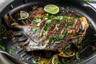 Limonlu kızarmış Dory balığı ve tavada maydanoz. Vejetaryen sağlıklı yiyecekler. Gri arka plan. Üst görünüm.