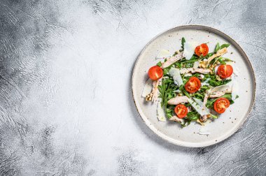 Tavuk, roka, ceviz, domates ve parmesanlı salata. gri arka plan. Üst Manzara. Boşluğu kopyala.