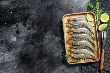 Taze çiğ kaplan karidesleri, tahta tepside karides. Siyah arka plan. Üst Manzara. Boşluğu kopyala.