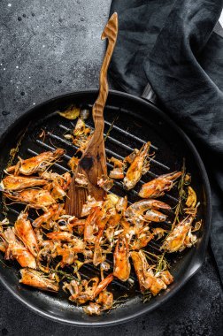 Arta kalan karidesler, tavada karidesler. Yiyecekler soyuldu, kafaların ayrıntıları verildi. Siyah arka plan. Üst görünüm.