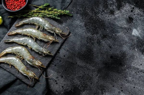 Whole fresh raw giant shrimps, prawns. Black background. Top view. Copy space.