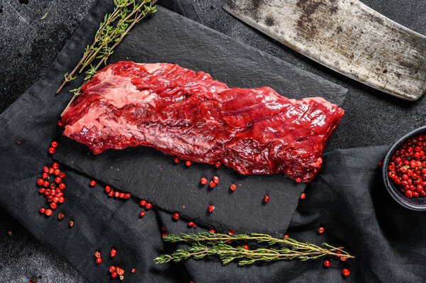 Raw skirt, machete steak with pink pepper and thyme. Black background. Top view.