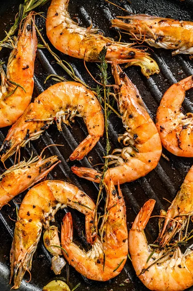 Grilled giant prawns, shrimps with garlic, lemon, spices in pan. Black background. Top view.