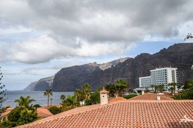 Volkanik kıyı manzarası, kırmızı kiremit çatı villaları, Atlantik okyanusu. Seçici odaklanma. Los Gigantes, Tenerife.
