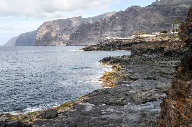 Siyah kayalar, oteller ve Atlantik Okyanusu ile volkanik sahilin manzarası. Seçici odaklanma. 20.01.2020 Los Gigantes, Tenerife.