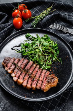 Kızarmış biftek, roka soslu mermer et. Siyah arka plan. Üst görünüm.