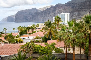 Volkanik kıyı manzarası, kırmızı kiremit çatı villaları, Atlantik okyanusu. Seçici odaklanma. Los Gigantes, Tenerife.