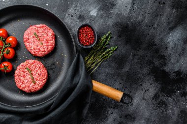 Çiğ kıymalı et pirzolası, tavada köfte. Siyah arka plan. Üst görünüm.