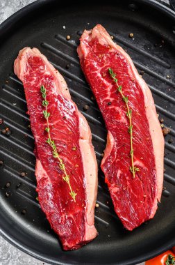 Izgara tavasında çiğ fileto biftek, yemek için malzemeler. Gri arka plan. Üst görünüm.