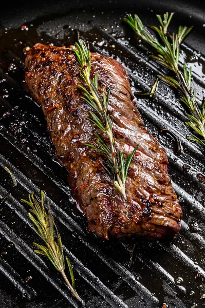 Cooked Vegas strip steak in a pan. Marble meat beef. Gray background. Top view.