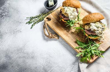 Mavi peynirli ev yapımı hamburger, mermer biftek, soğan reçeli ve roka. Gri arka plan. Üst Manzara. Boşluğu kopyala.