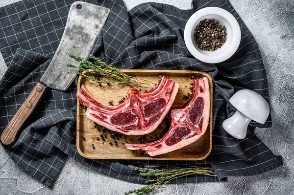 Raw lamb meat on ribs with rosemary and spices. Gray background. Top view.