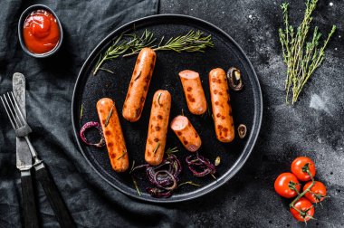 Izgara domuz sosisi soğanlı, sarımsaklı ve biberiyeli. Siyah arka plan. Üst görünüm.