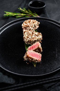 Tabakta ızgara ton balığı bifteği. Siyah arka plan. Üst görünüm.