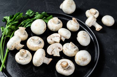 Tabakta taze mantar şampiyonu. Siyah arka plan. Üst görünüm.