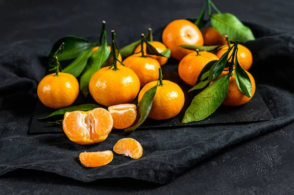 Tangerines, mandarines with leaves. Black background. Top view.