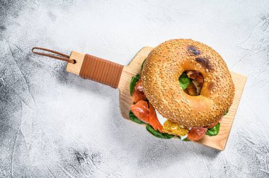 Somonlu bagel sandviç, krem peynir, ıspanak ve yumurta. Gri arka plan. Üst görünüm.
