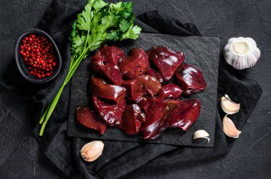 Taş tahtada çiğ tavuk ciğeri. Siyah arka plan. Üst görünüm.