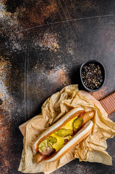 Hot dog with chicken sausage on a wooden cutting Board in Kraft paper, fast food restaurant menu concept. Junk food. Space for text.