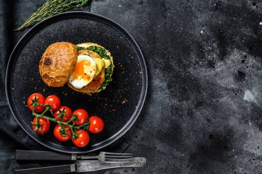 Balık fileto, yumurta ve ıspanaklı nefis balık burgeri. Siyah arka plan. Üst Manzara. Boşluğu kopyala.